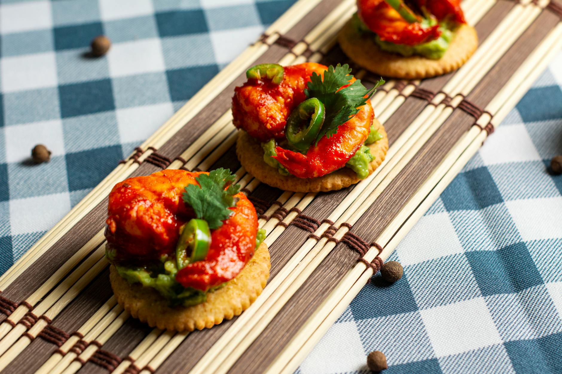 Tasty shrimp appetizers with guacamole and jalapeños served on crackers.