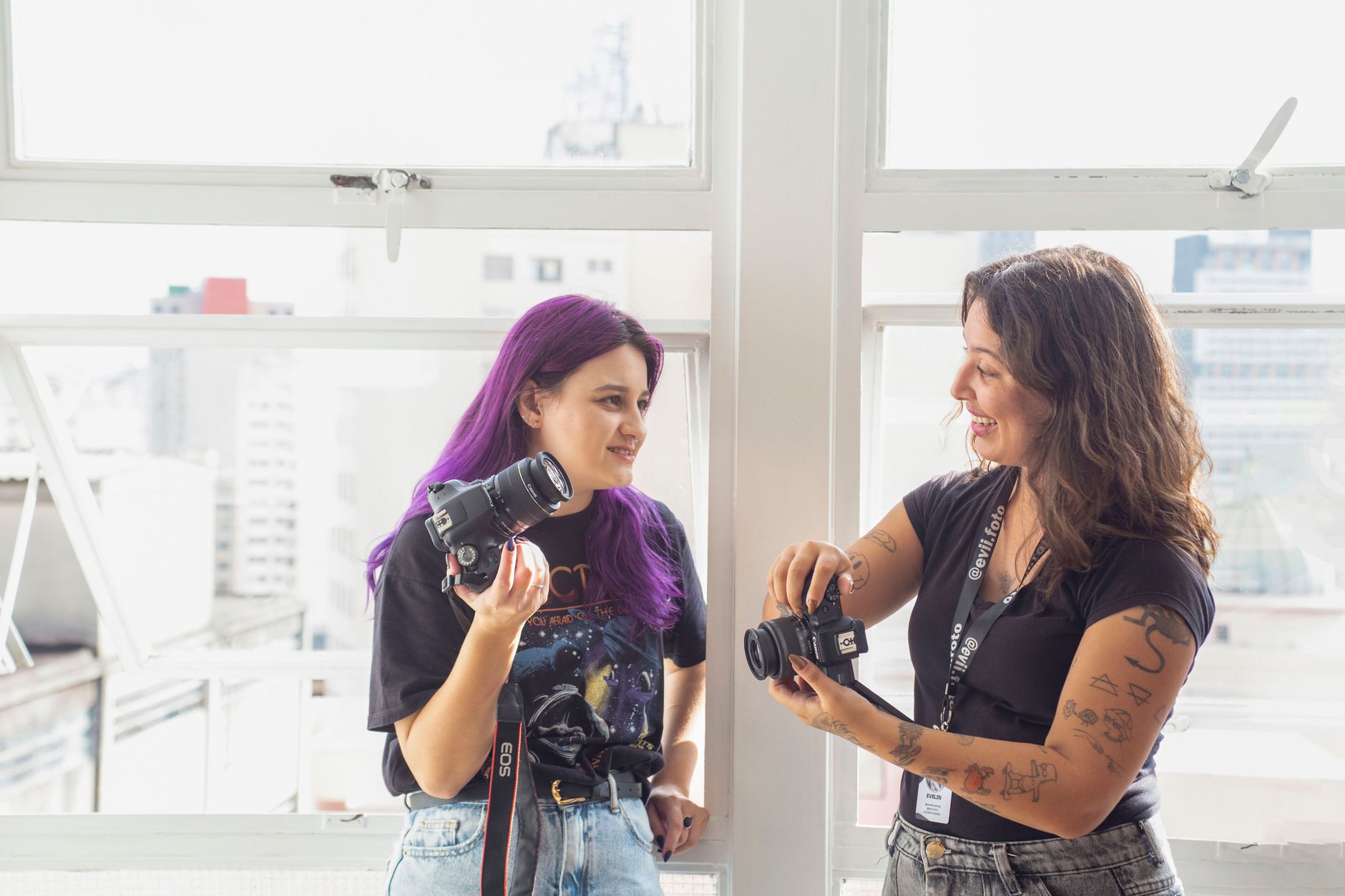 Two women photographers exchanging tips indoors, showcasing a creative workspace.