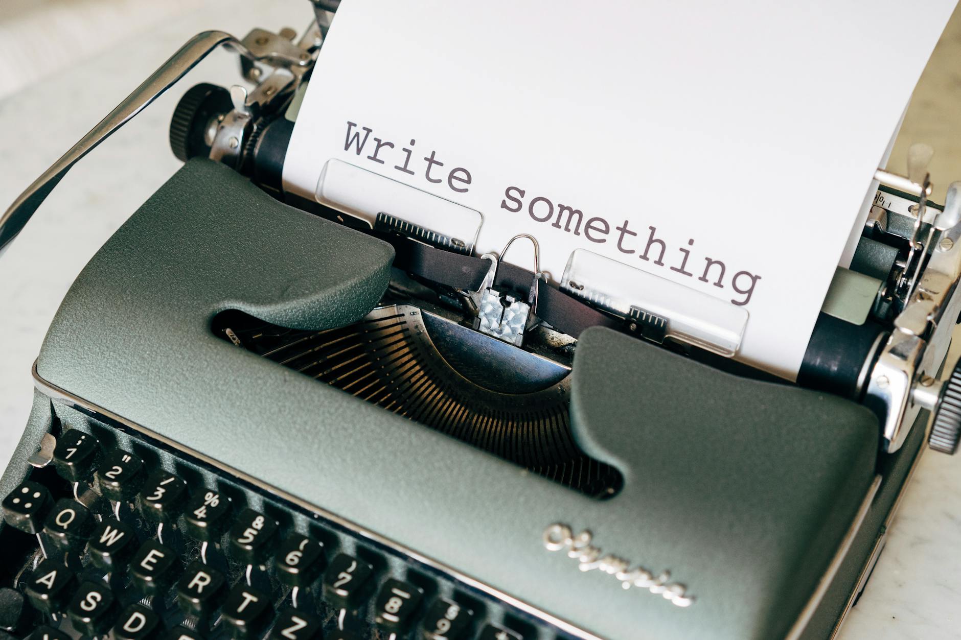 A close-up of a vintage typewriter with 'Write something' typed on paper.