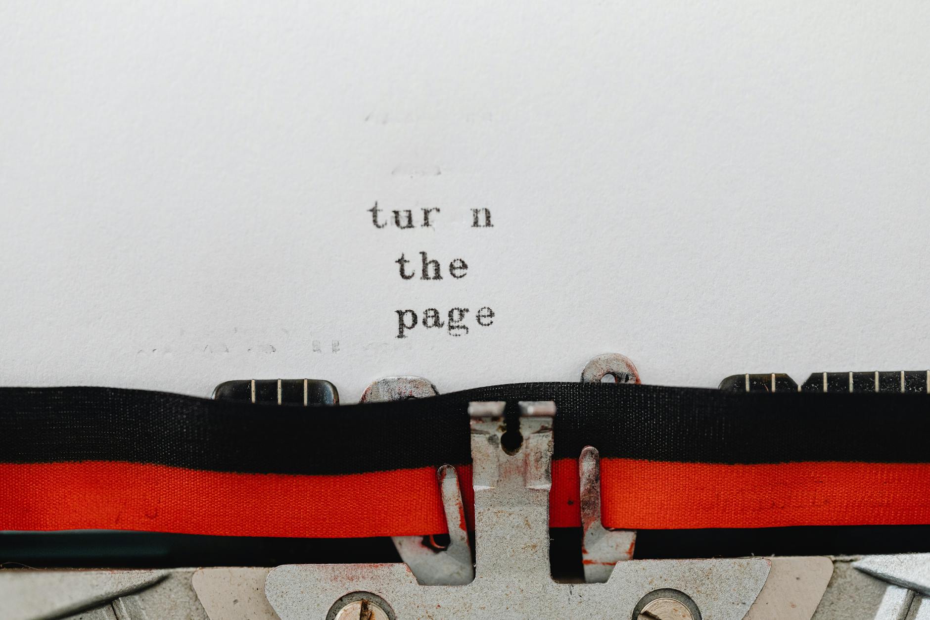 Close-up of a vintage typewriter with text 'turn the page' typed on paper, symbolizing change and new beginnings.